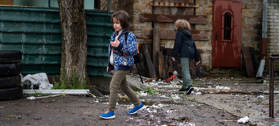 Crianças passam por uma casa destruída em Kherson, Ucrânia.