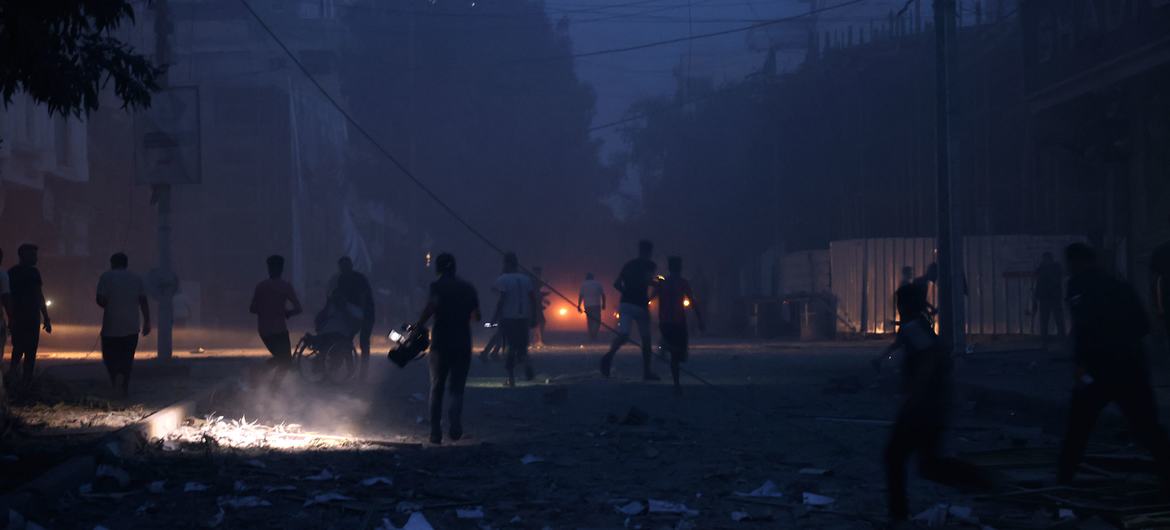 Pessoas caminham entre os escombros na escuridão em Rafah devido a uma queda de energia