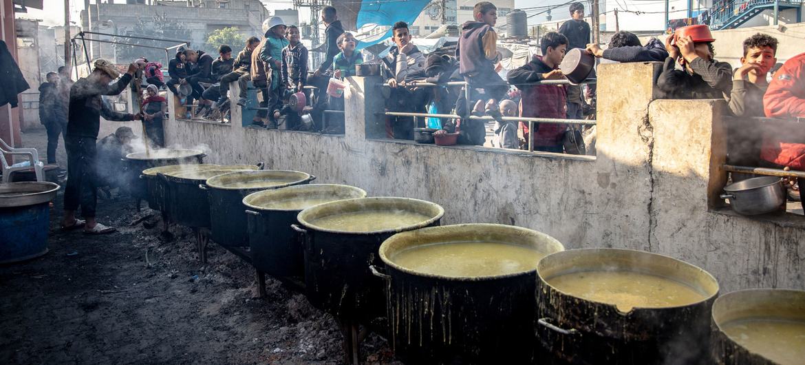 Palestinos deslocados esperam por comida no campo de Al-Shaboura, em Rafah